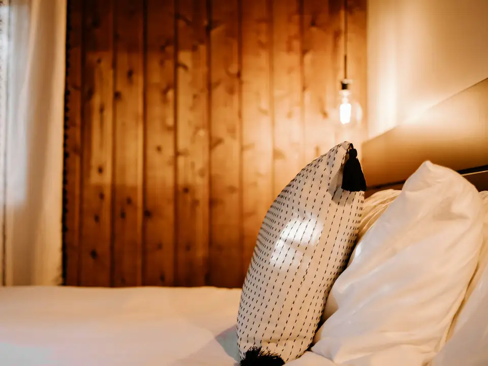 Cama con acolchado blanco y respaldo de madera