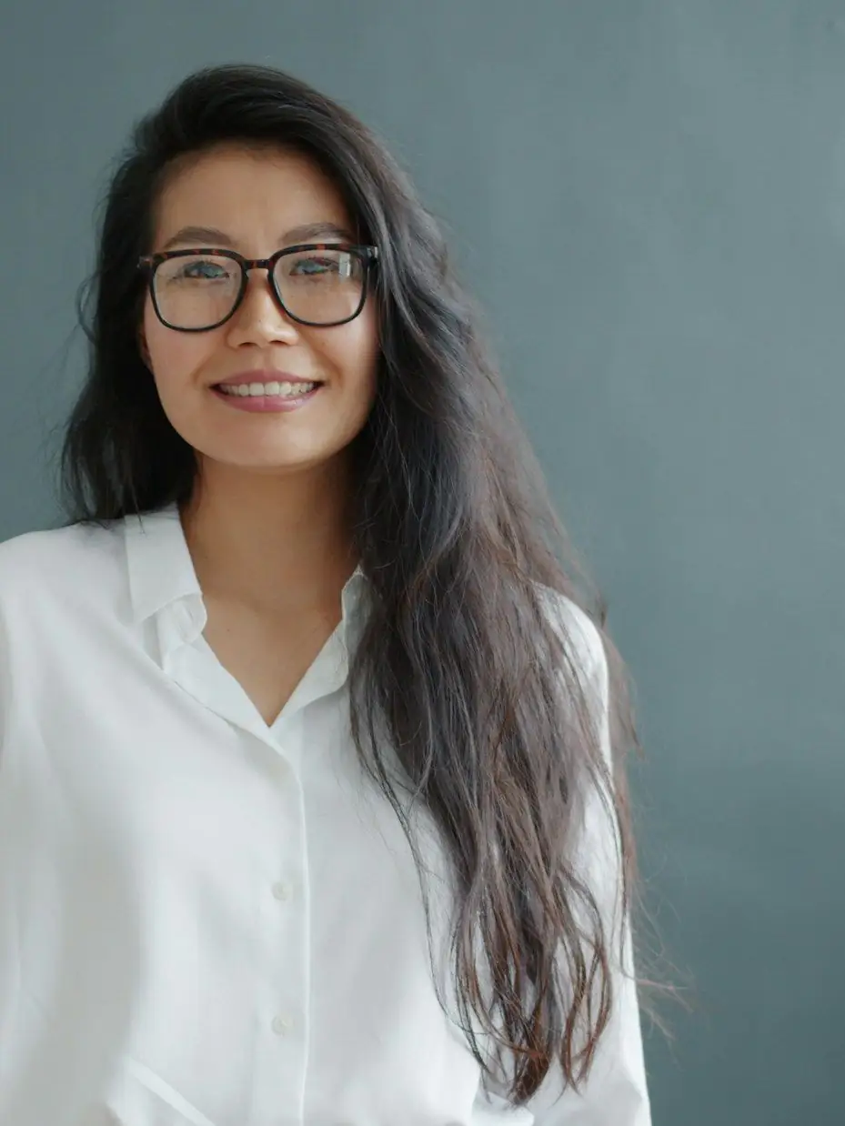 Retrato de Lucía Méndez, sonriente, con lentes y camisa blanca