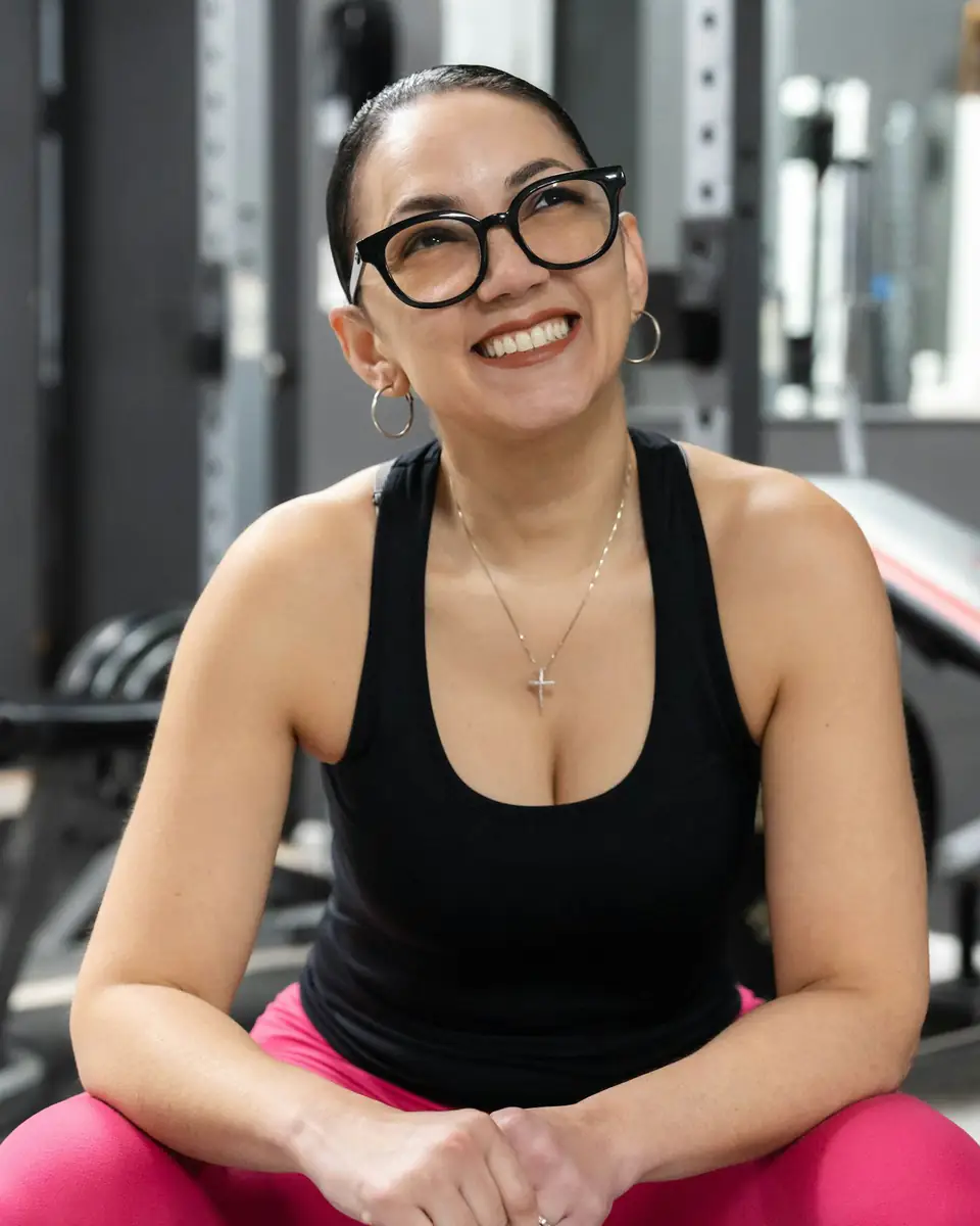 Lucía, sonriente, sentada en un banco de la sala de musculación