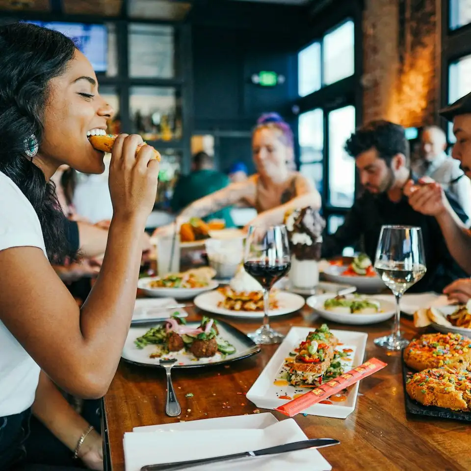 Una clienta disfrutando la comida en una mesa llena de platos