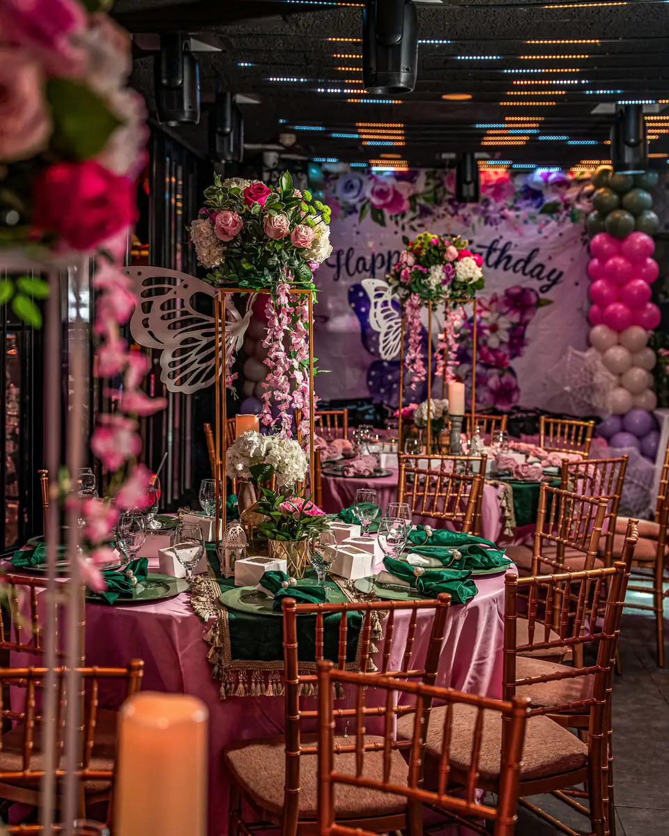 Mesas de un cumpleaños de 15 con flores, globos y velas