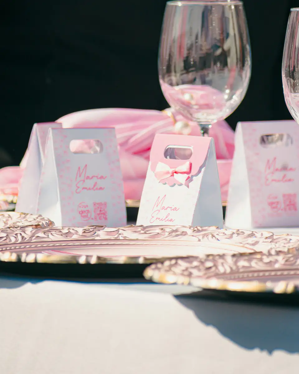 Bolsitas de recuerdo rosadas junto a copas en la mesa