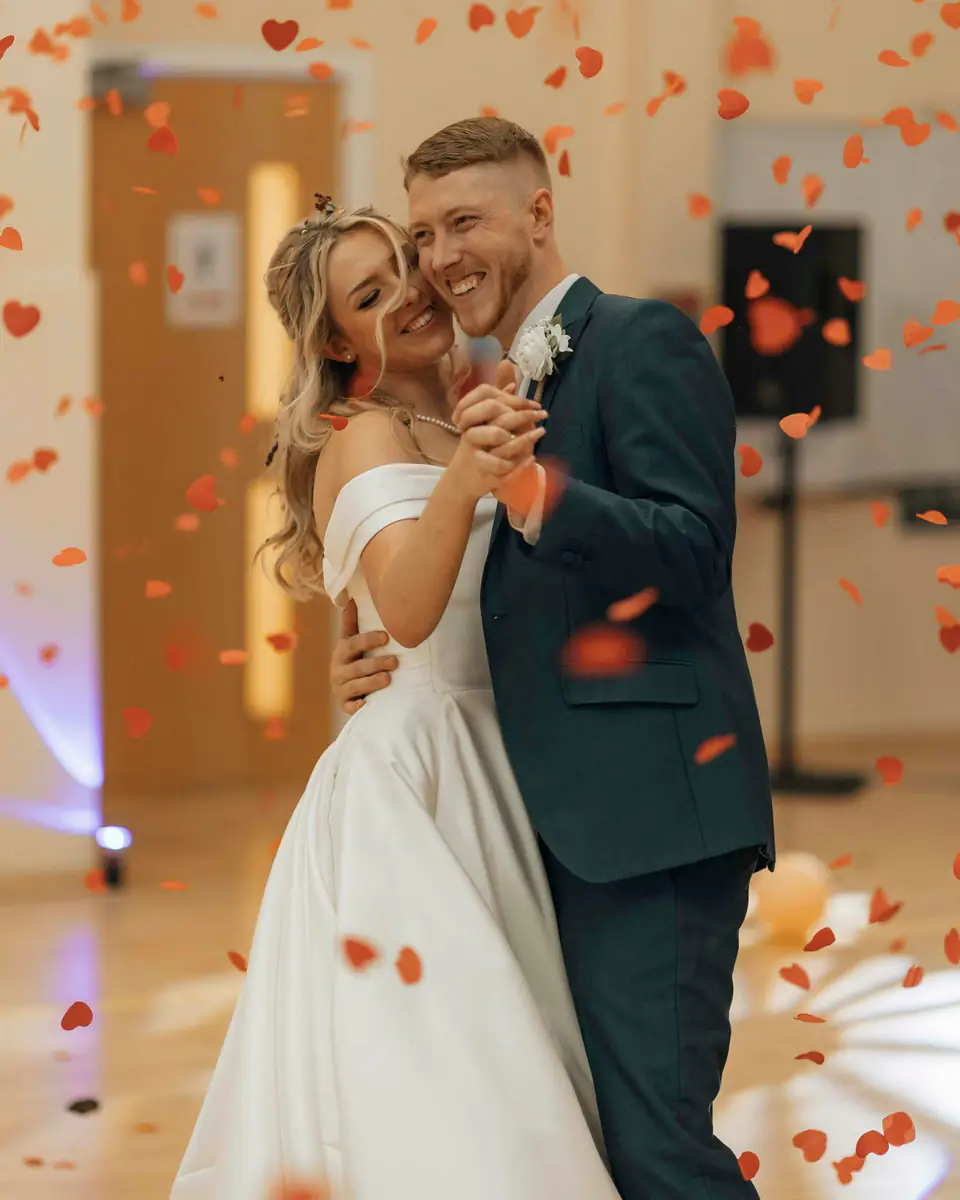 Los novios bailan el vals entre pétalos que caen