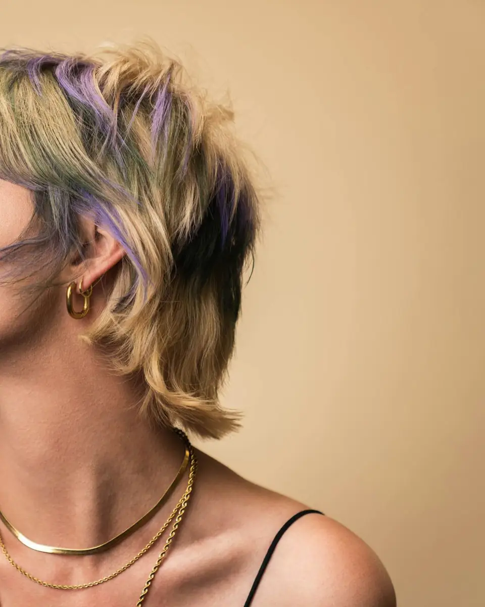 Perfil de una mujer con corte shag y mechas lila y verde agua