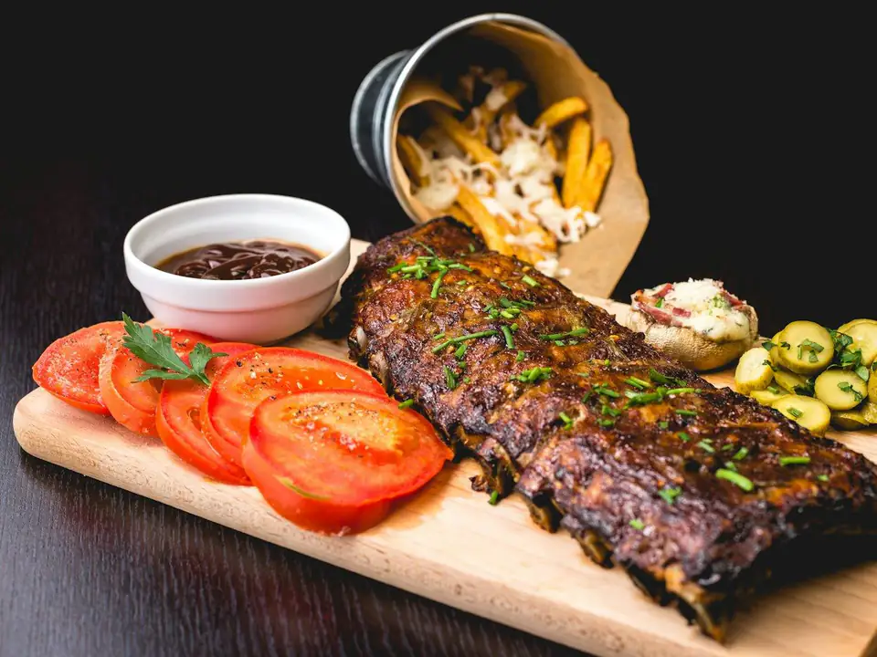 Tira de asado a la parrilla sobre una tabla con rodajas de tomate
