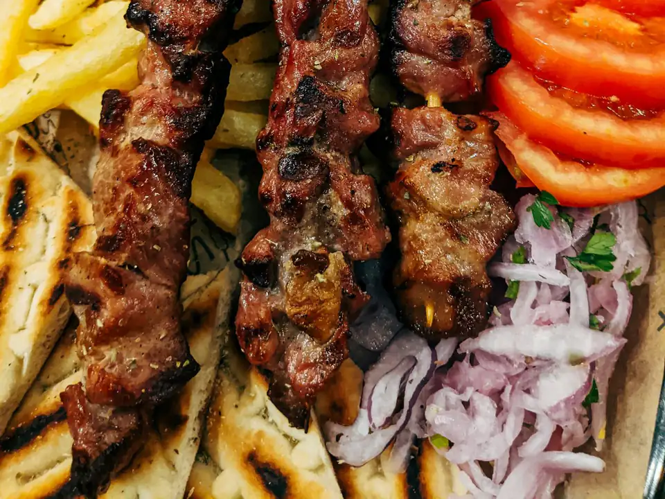 Brochettes de carne a la parrilla con papas fritas y tomate
