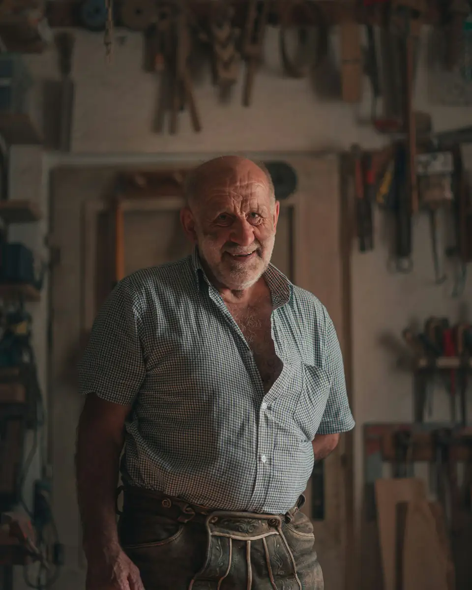 Walter Pereira, carpintero, de pie en su taller con herramientas colgadas detrás