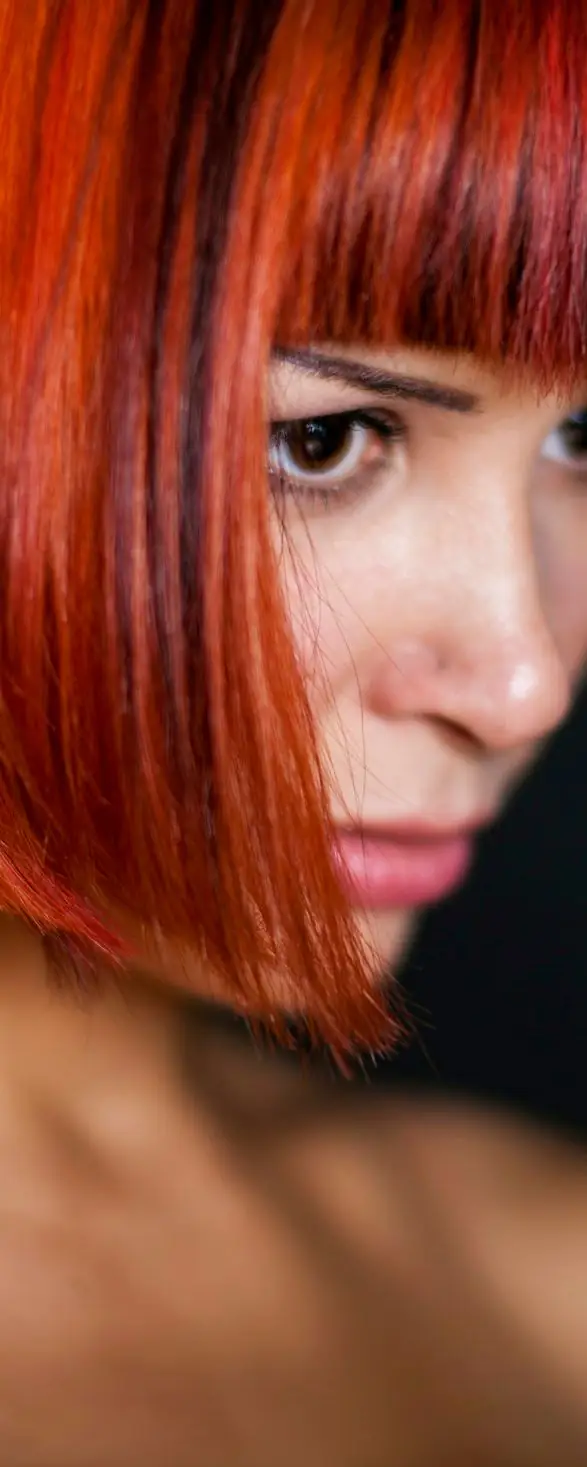 Una mujer con el pelo rojo intenso, cortado en carré con flequillo